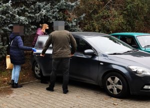 Na zdjęciu widoczni nieumundurowani policjanci wraz z zatrzymaną kobieta, którą prowadzą do radiowozu.