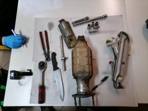 Na zdjęciu widoczny skradziony katalizator oraz narzędzia jak nóż, śrubokręty, lewarek i szczypce.