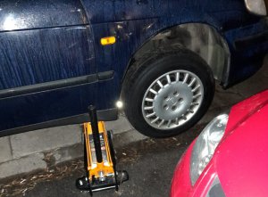 Na zdjęciu widoczny pojazd koloru granatowego, który ma podstawiony lewarek