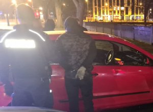 Na zdjęciu widoczny zatrzymany mężczyzna, którego za rękę trzyma umundurowany policjant.