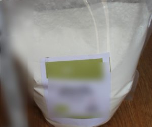 Na zdjęciu widoczny worek foliowy z zawartością białej sypkiej substancji.