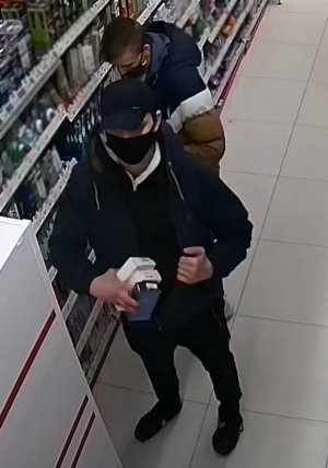 Na zdjęciu widoczni dwa mężczyźni. Jeden z nich ma założoną czarna kurtkę i czarną czapkę z daszkiem, drugi ma kurtkę w pasy koloru granatowo-biało beżowym.