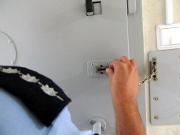 Na zdjęciu widoczny umundurowany policjant, który zamyka drzwi od pomieszczenia dla osób zatrzymanych.