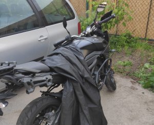 Na zdjęciu widoczny motocykl, który ma narzucony czarny pokrowiec.
