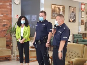 Na zdjęciu widocznych dwóch umundurowanych policjantów w pomieszczeniu domu wsparcia. Wraz z nimi stoi przedstawiciel wolskiej delegatury biura bezpieczeństwa i zarządzania kryzysowego.
