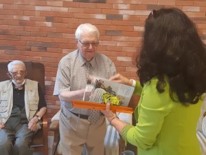 Na zdjęciu widoczny weteran powstania, który otrzymuje ulotkę nt. działania oszustom na tzw. "policjanta" oraz odblaski.