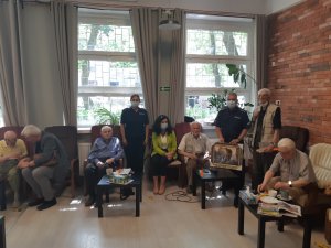 Na zdjęciu widoczni umundurowani policjanci, którzy stoją obok weteranów powstania do zdjęcia pamiątkowego.