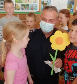 Na zdjęciu widoczny umundurowany policjant, który jest w pomieszczeniu przedszkolnym z dziećmi.