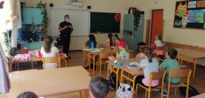 Na zdjęciu widoczny umundurowany policjant wraz z dziećmi w pomieszczeniu szkolnym.