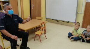 Na zdjęciu widoczny umundurowany policjant i dzieci.