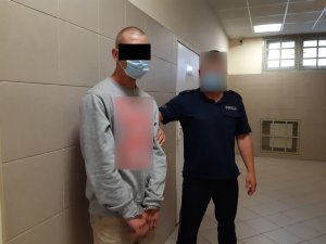 Na zdjęciu widoczny zatrzymany mężczyzna, który stoi przy umundurowanym policjancie.