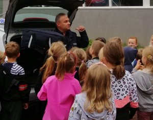 Na zdjęciu widoczny umundurowany policjant wraz z dziećmi.