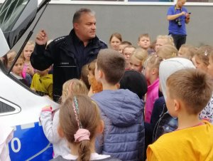 Na zdjęciu widoczny umundurowany policjant wraz z dziećmi.