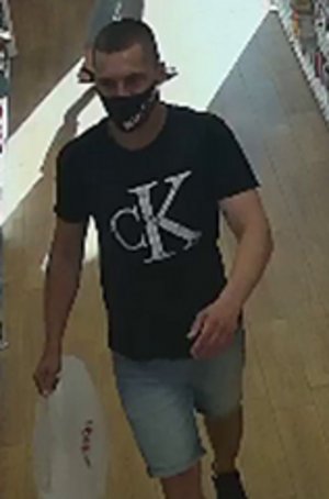 Na zdjęciu widoczny mężczyzna w czarnej koszulce z napisem CK, ma spodenki typu jeans krótkie do kolan.