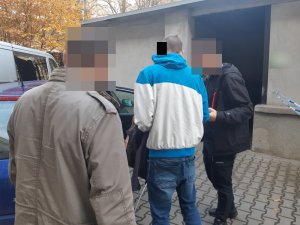 Na zdjęciu widoczni nieumundurowani policjanci wraz z zatrzymanym mężczyzną.