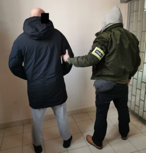 Na zdjęciu widoczny nieumundurowany policjant wraz z zatrzymanym mężczyzną.