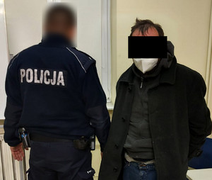 Na zdjęciu widoczny umundurowany policjant i zatrzymany mężczyzna.