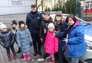 Na zdjęciu widoczny umundurowany policjant i dzieci stojące przed radiowozem..
