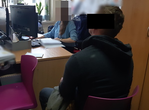 Na zdjęciu widoczna nieumundurowana policjantka, która przesłuchuje podejrzanego mężczyznę.