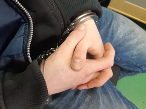 Na zdjęciu widoczne ręce zatrzymanego, ma założone kajdanki.