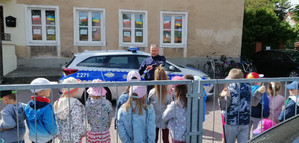 Na zdjęciu widoczny radiowóz, umundurowany policjant i dzieci.