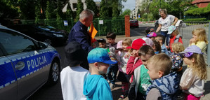 Na zdjęciu widoczny radiowóz, umundurowany policjant i dzieci.