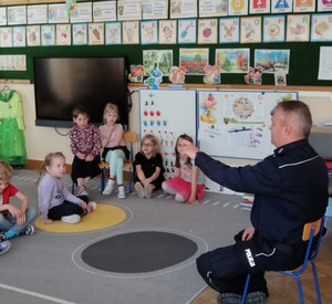 Na zdjęciu widoczny umundurowany policjant i dzieci.