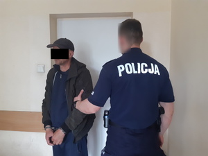 Na zdjęciu widoczny umundurowany policjant i zatrzymany mężczyzna.