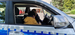 Na zdjęciu widać umundurowanego policjanta i dziecko siedzących w radiowozie.