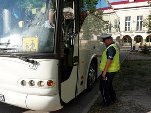 Na zdjęciu widoczny umundurowany policjant i autobus.