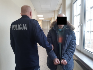 Na zdjęciu widoczny umundurowany policjant i zatrzymany mężczyzna.