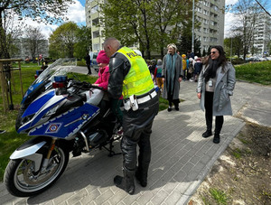 Na zdjęciu widać umundurowanego policjanta, motocykl policyjny i dzieci.