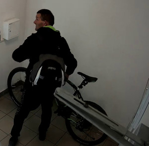 Na zdjęciu widać mężczyznę, który trzyma rower.