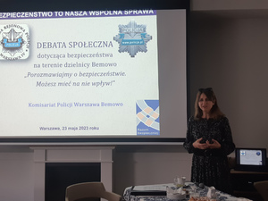 Na zdjęciu widać kobietę i wyświetlony slajd dotyczący debaty.