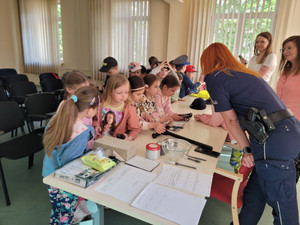 Na zdjęciu widać dzieci siedzące przy stole wraz z policjantem.