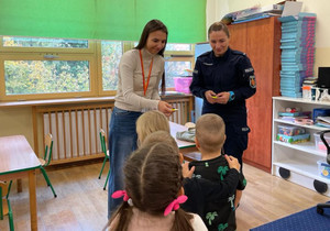 Policjantka z kobietą wręcza odblaski.