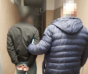 Policjant trzyma zatrzymanego.