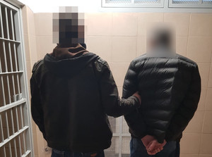 Policjant trzyma zatrzymanego.