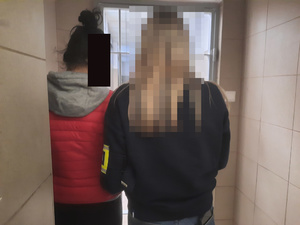 Policjantka stoi obok zatrzymanej.