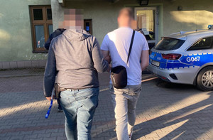 Policjant prowadzi zatrzymanego.