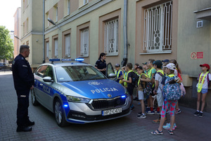Policjanci, radiowóz i uczniowie.