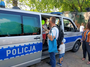 Radiowóz i osoby na pikniku.