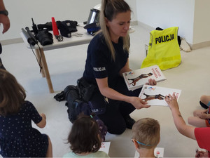 Policjantka rozdaje dzieciom książeczki.