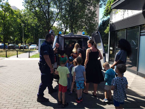 Policjanci,radiowóz i dzieci z opiekunami.