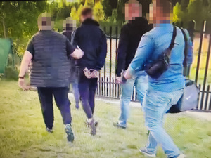 Policjanci prowadzą zatrzymanego.