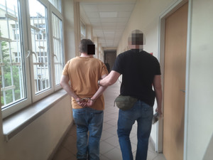 Policjant prowadzi zatrzymanego.