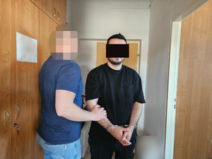 Policjant trzyma zatrzymanego.