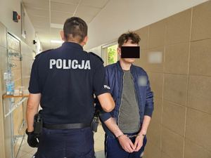 Policjant trzyma zatrzymanego.
