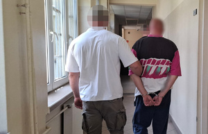 Policjant prowadzi zatrzymanego.