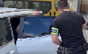 Policjant wprowadza zatrzymanego do pojazdu.
